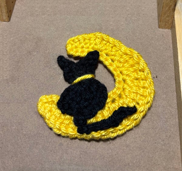 Black cat sitting on a yellow moon.